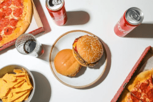 burger, chips, pizza, and cold drinks on a table