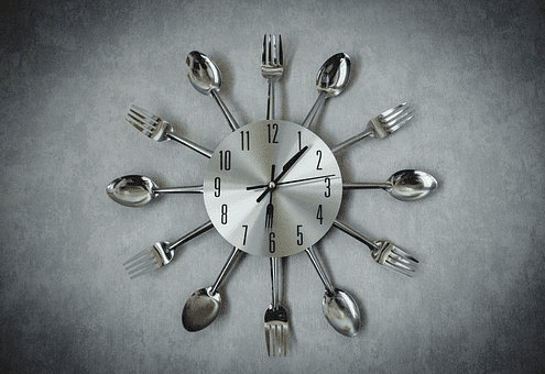 spoons and forks arranged around a wall clock