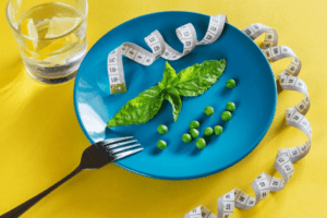 a plate with fork and peas and measuring tape with a glass of water