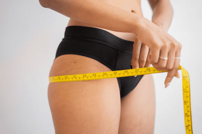 A person measuring weight loss with the help of a measuring tape